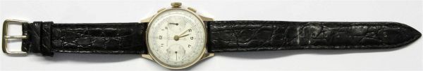 Herren-Armbanduhr  BAUME & MERCIER Telemetre, um 1960. Vergoldete Lunette (Durchmesser 33 mm), Aufziehwerk, Sekundenanzeige und Stoppfunktion. Schwarzes Lederarmband. Zifferblatt Fleck, Stoppfunktion klemmt, Werk läuft, getragen