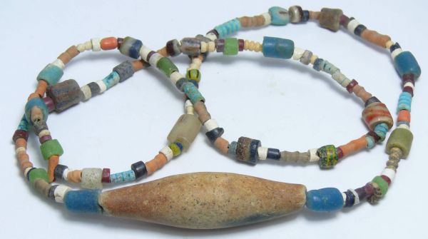 Egypte - Collier de perles diverses (grosse perle) - fin 1000 av. J.-C. Très beau collier en perles de silice et perles en pâte de verre de couleurs variées, se terminant par une grosse perle tubulaire conique de couleur marron clair avec un reste de polychromie bleu foncé. 290 mm et 56 mm pour la grosse perle tubulaire conique.