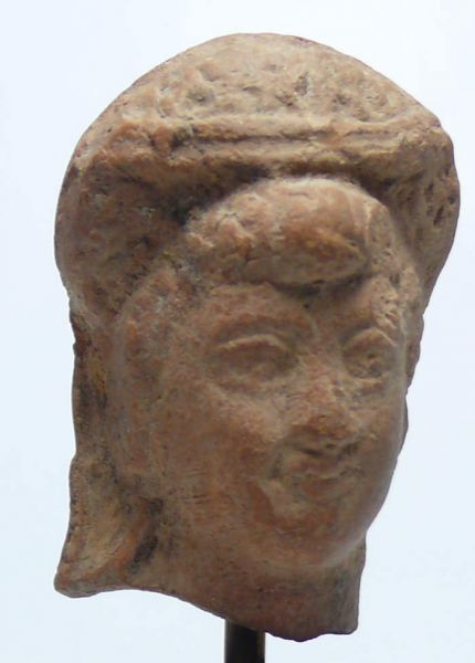 Egypte - Epoque romaine - Tête féminine en terre cuite - 30 av / 200 ap J.-C. Jolie tête féminine en terre cuite de couleur marron clair. Le personnage a les traits fins et les cheveux coiffés, paré d'un diadème ou d'un ruban. 53 mm.