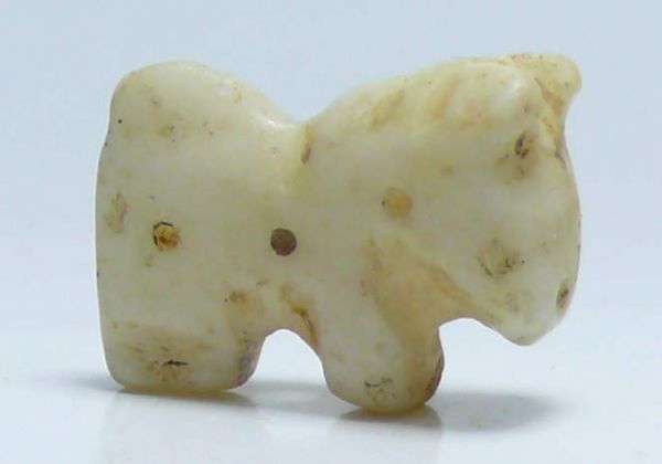 Proche-Orient - Animal en calcite - 3000 av. J.-C. Petit animal en calcite de couleur blanche. L'objet est percé de part en part sans doute pour servir de perle sur un bijou. 18 mm.