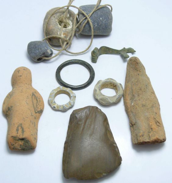 Epoques diverses - Lot de 10 objets Petites statuettes en terre cuite, hâche polie, 3 rouelles,  perles antiques et fibule en forme de chien. De 20 à 80 mm.