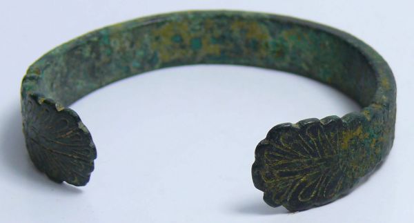 Romain - Bracelet en bronze (Palmes)  - 100 / 300 ap. J.-C. Bracelet plat en bronze orné d'une frise d'annelets se terminant par 2 palmes. 60 mm.